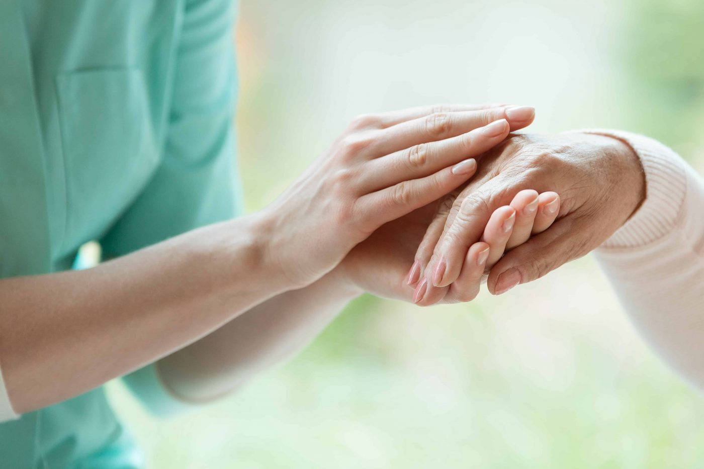 Caretaker massaging pensioner’s hand Young caretaker massaging pensioner's hand with Parkinson's disease