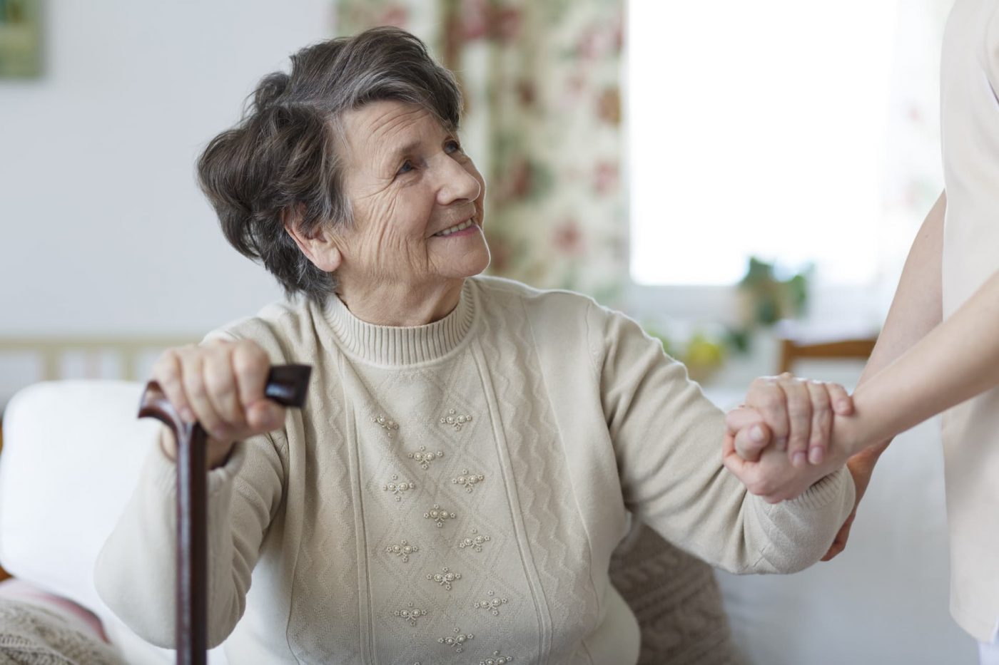 Smiling senior woman holding a cane and looking at her caregiver